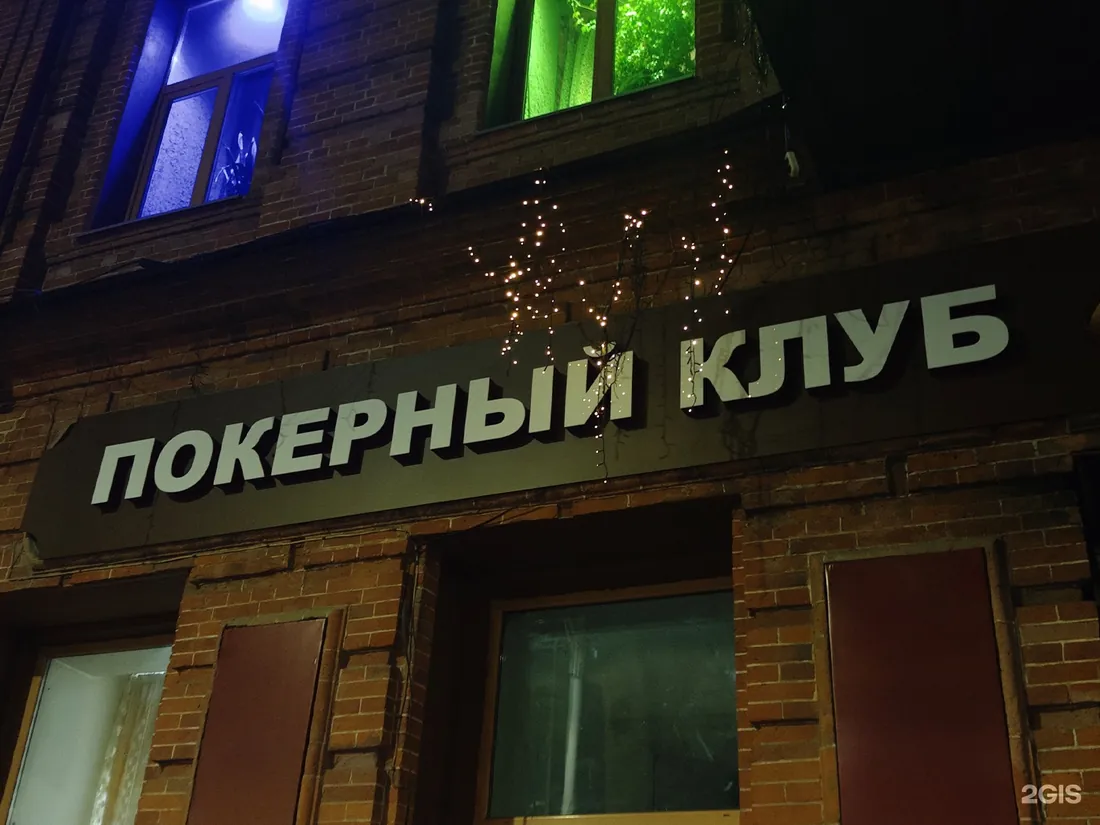 Кирпичный фасад вечером с вывеской «Покерный клуб»